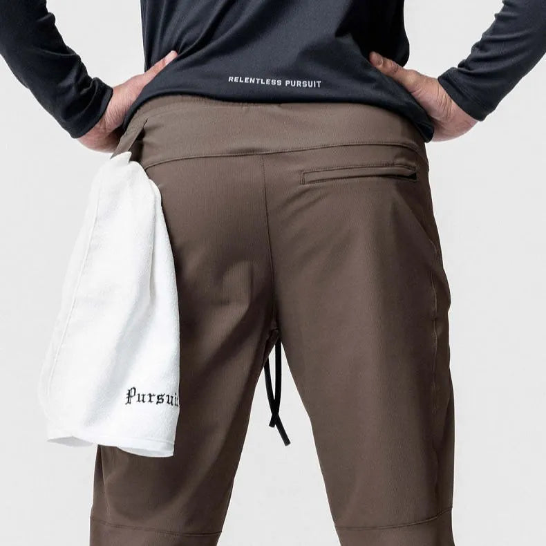 Man wearing dark grey loose-fit fitness trousers with tied ankle cuffs, suitable for gym training.