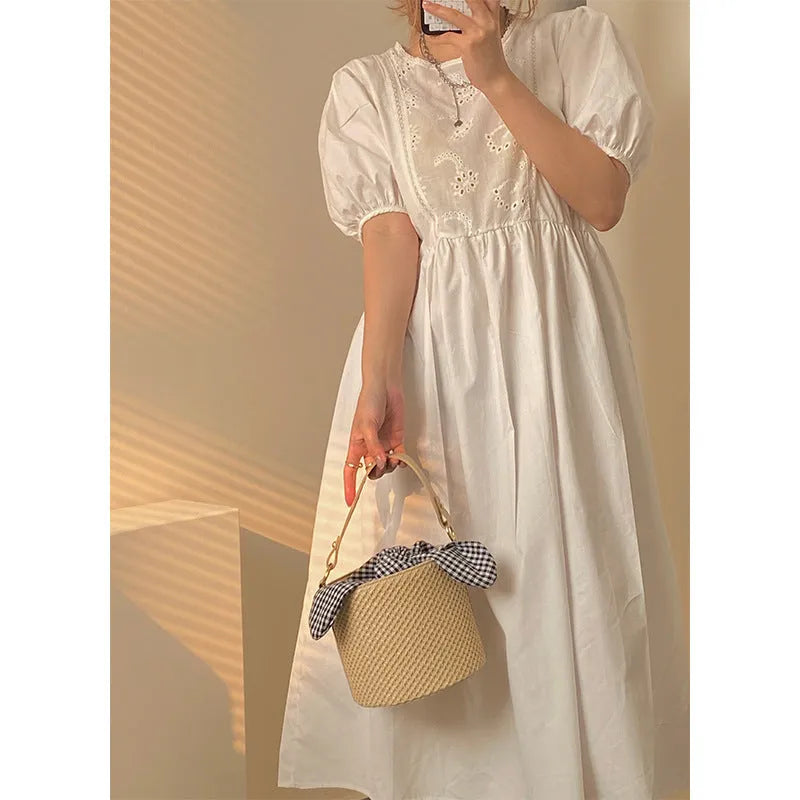 Women's medium beige PU bucket straw bag with open top and messenger strap on neutral background