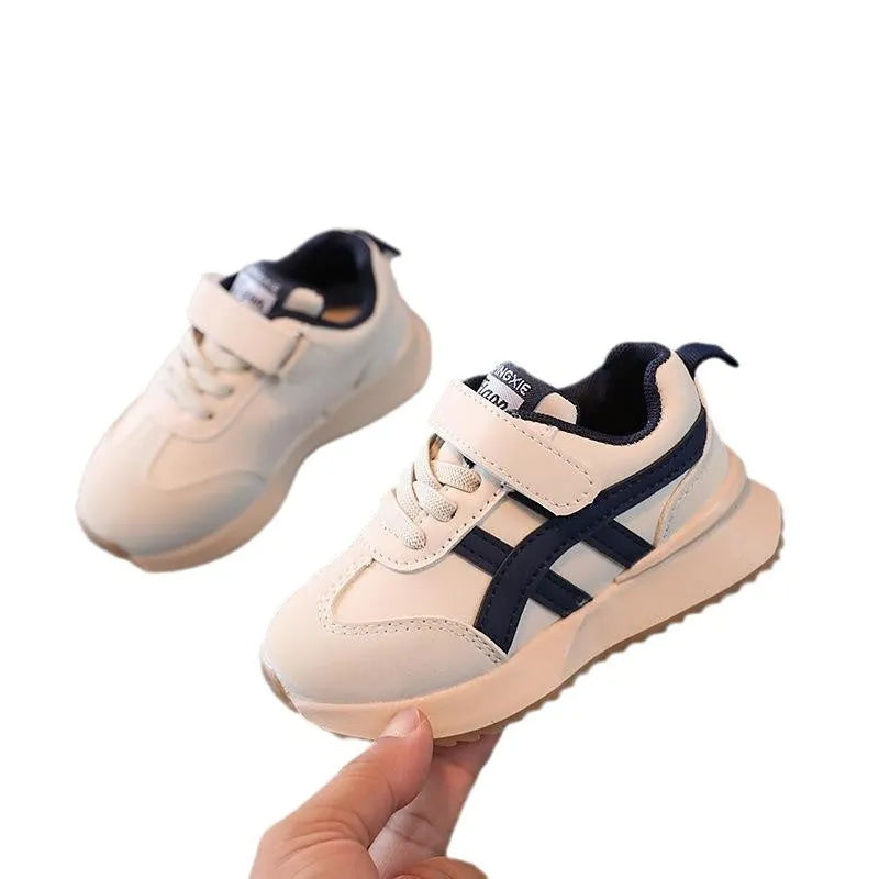 Children's white velcro sneakers with synthetic leather upper and rubber sole on a neutral background.