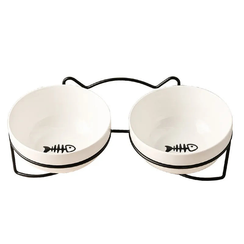 White ceramic cat bowl with cat footprint design on a black iron stand with cat ears.