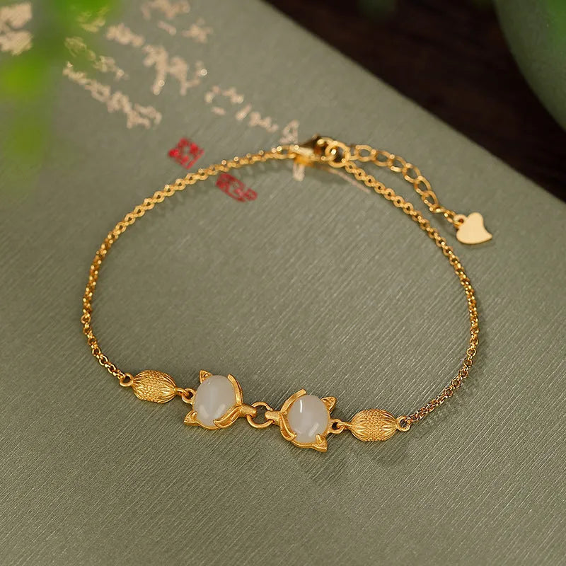 Close-up of a women's silver bracelet with a detailed fox charm and a round stone bead on an adjustable chain.