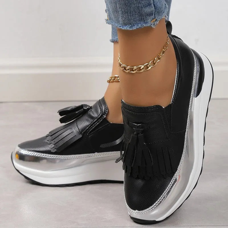 Black women's platform shoes with a tassel on the front and a thick muffin wedge heel.