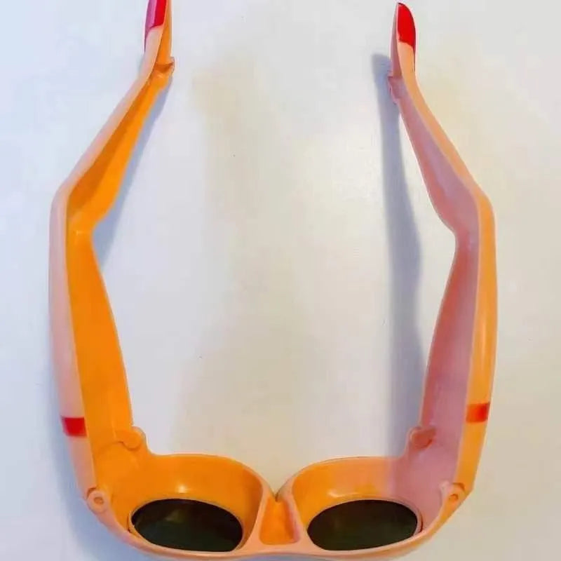 Orange novelty sunglasses with a unique leg-hip frame design, shown from the front. Oversized 15cm by 20cm dimensions.