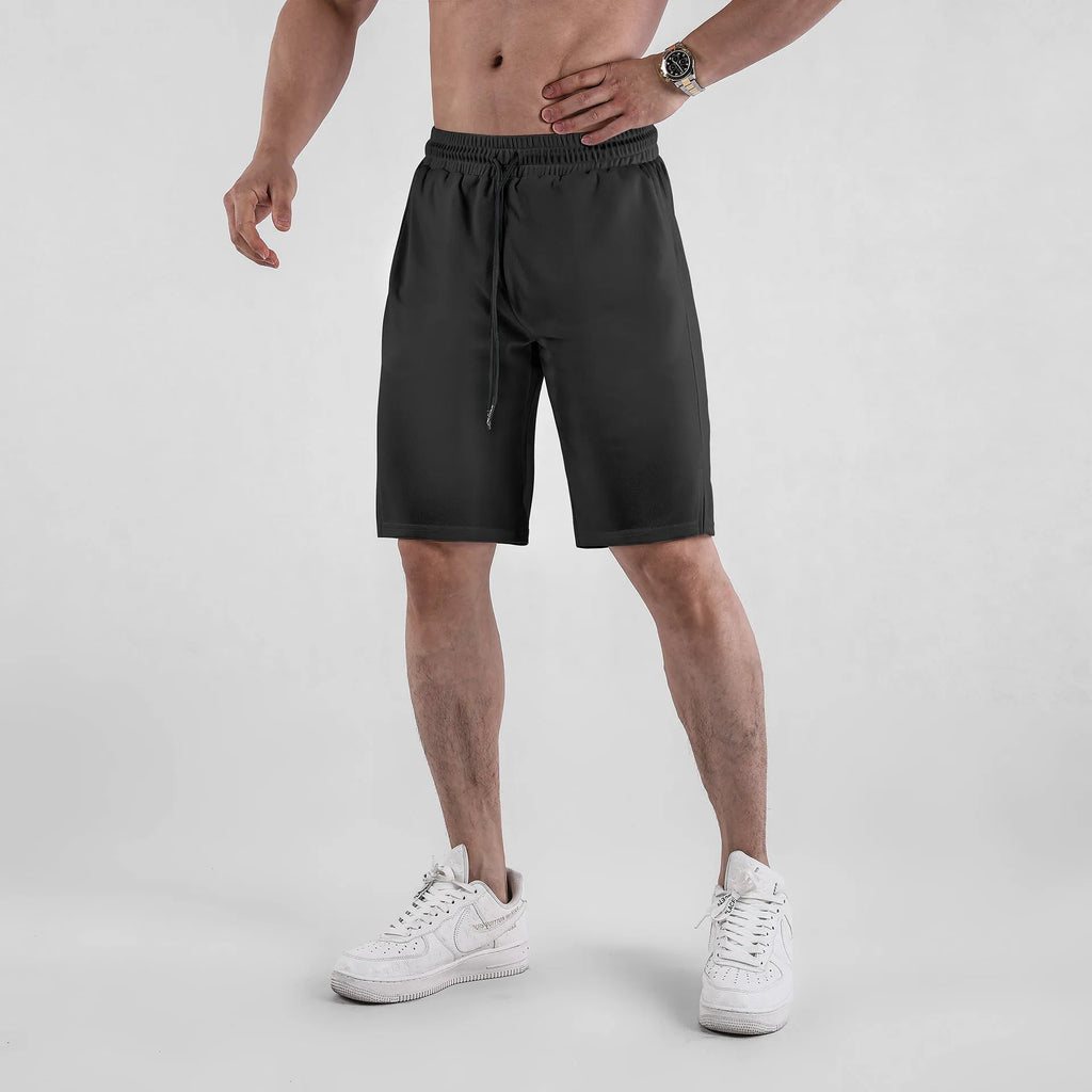 Man wearing loose-fit black quick-dry mesh shorts for casual summer sportswear.
