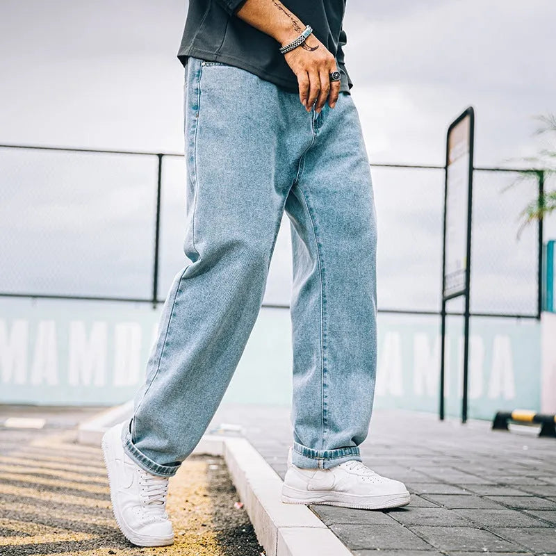 Men's dark blue loose straight-leg cotton jeans on a hanger, showing the simple style and mid-waist fit.