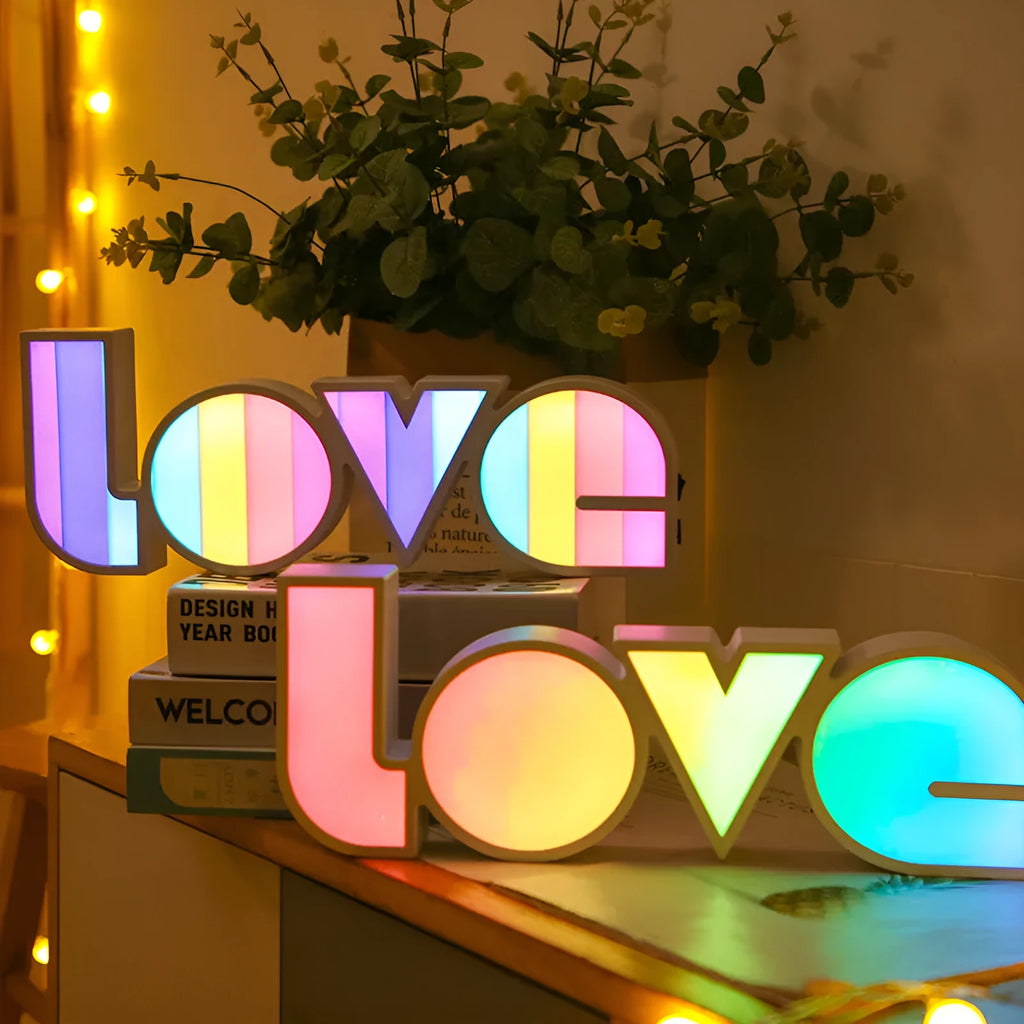LED LOVE light with rainbow-coloured plastic lampshade on a desk