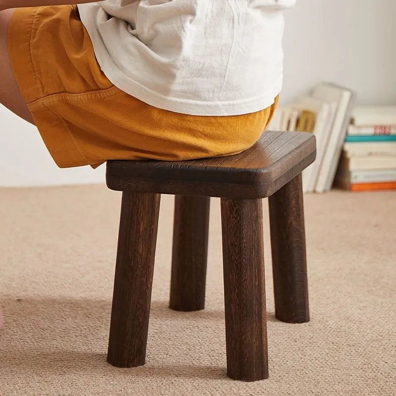 Solid wood shoe changing stool with a distressed finish and angular bracket frame.