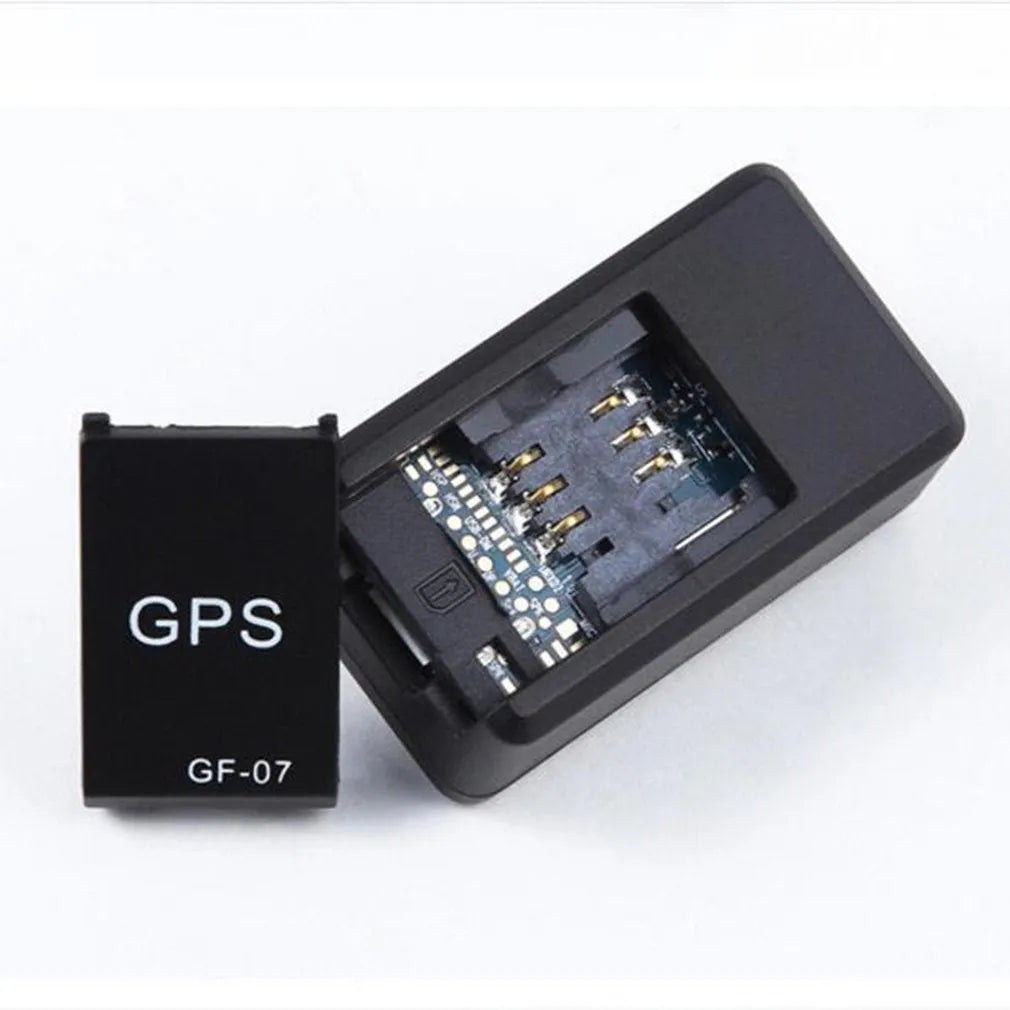 Small black magnetic GPS tracker device next to a USB charging cable on a table.