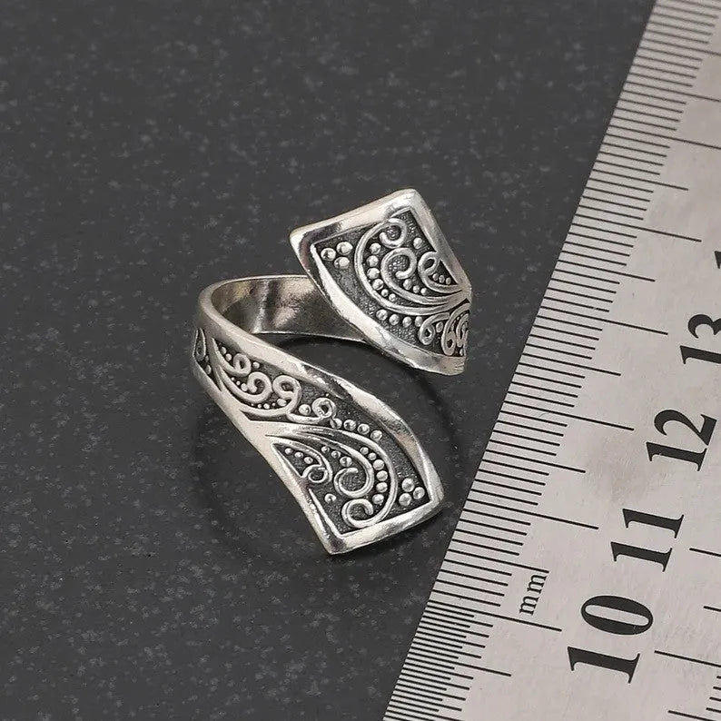 Silver-coloured adjustable minimalist women's ring with a retro design on a plain background.