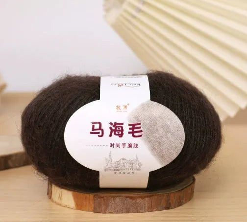 A ball of mohair yarn in a selected colour next to a hand-woven scarf example, showcasing the DIY kit.