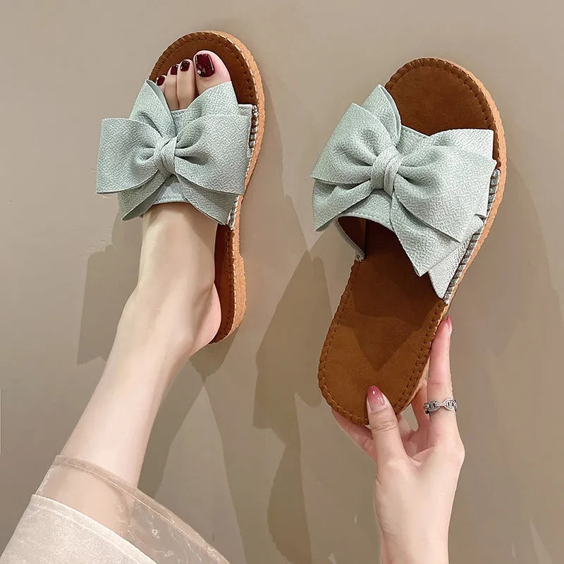 Women's beige suede slip-on sandals with bow detail and rubber sole