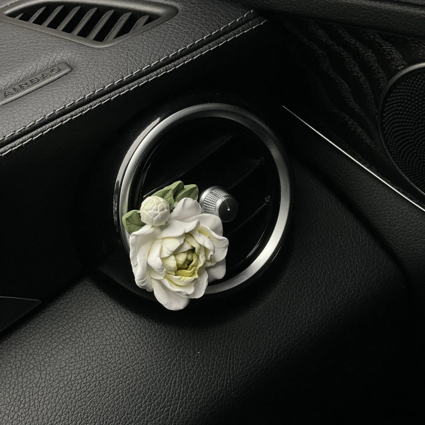 Solid jasmine car perfume diffuser clipped onto a car air vent, showing off white colour.