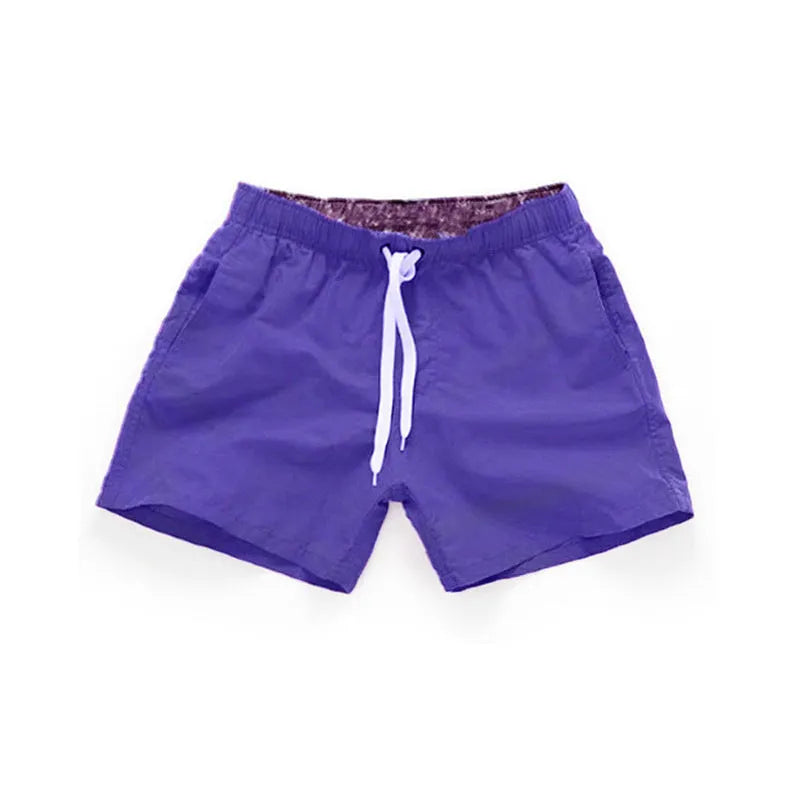 Men's polyester surf shorts in multiple colours on a beach background, showing straight leg design.