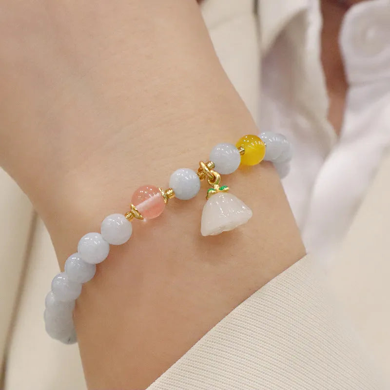 Gold plated bracelet with a detailed artificial crystal charm pendant on a woman's wrist.