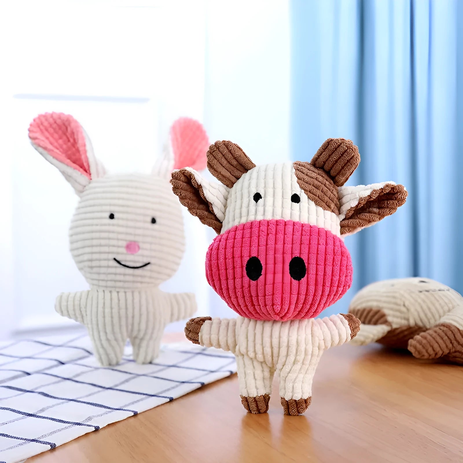 Animal shaped plush squeaky dog chew toy in assorted colours including blue, brown, and cow print.