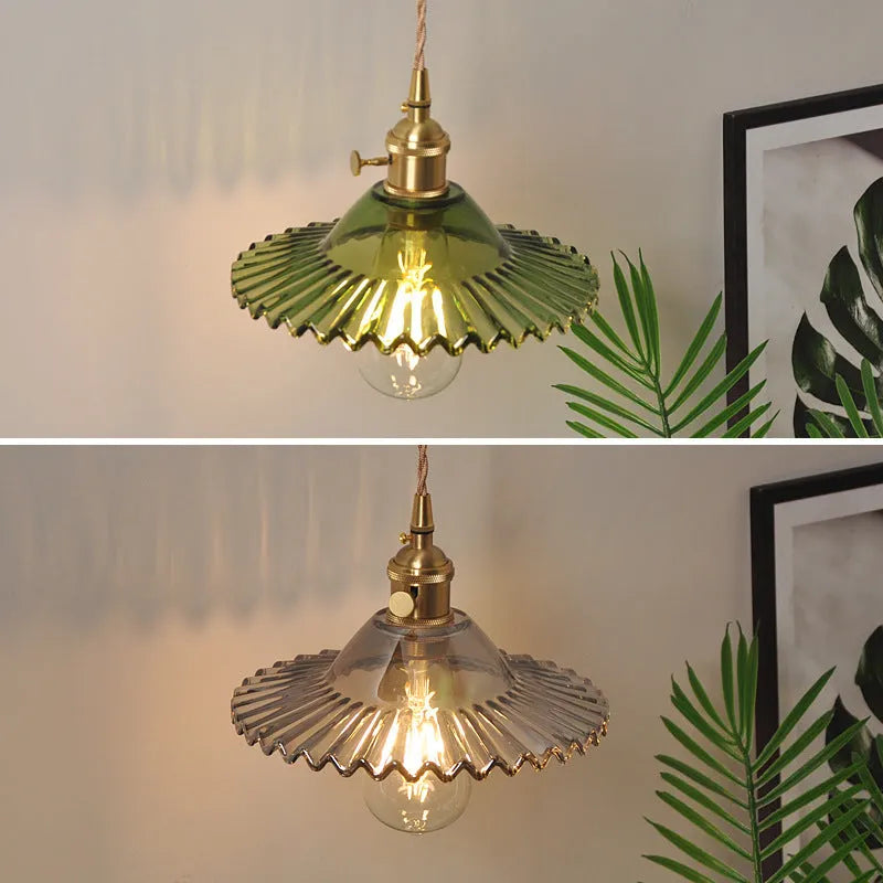 Brass wall lamp with an adjustable smoked grey glass lotus shade mounted beside a bed.