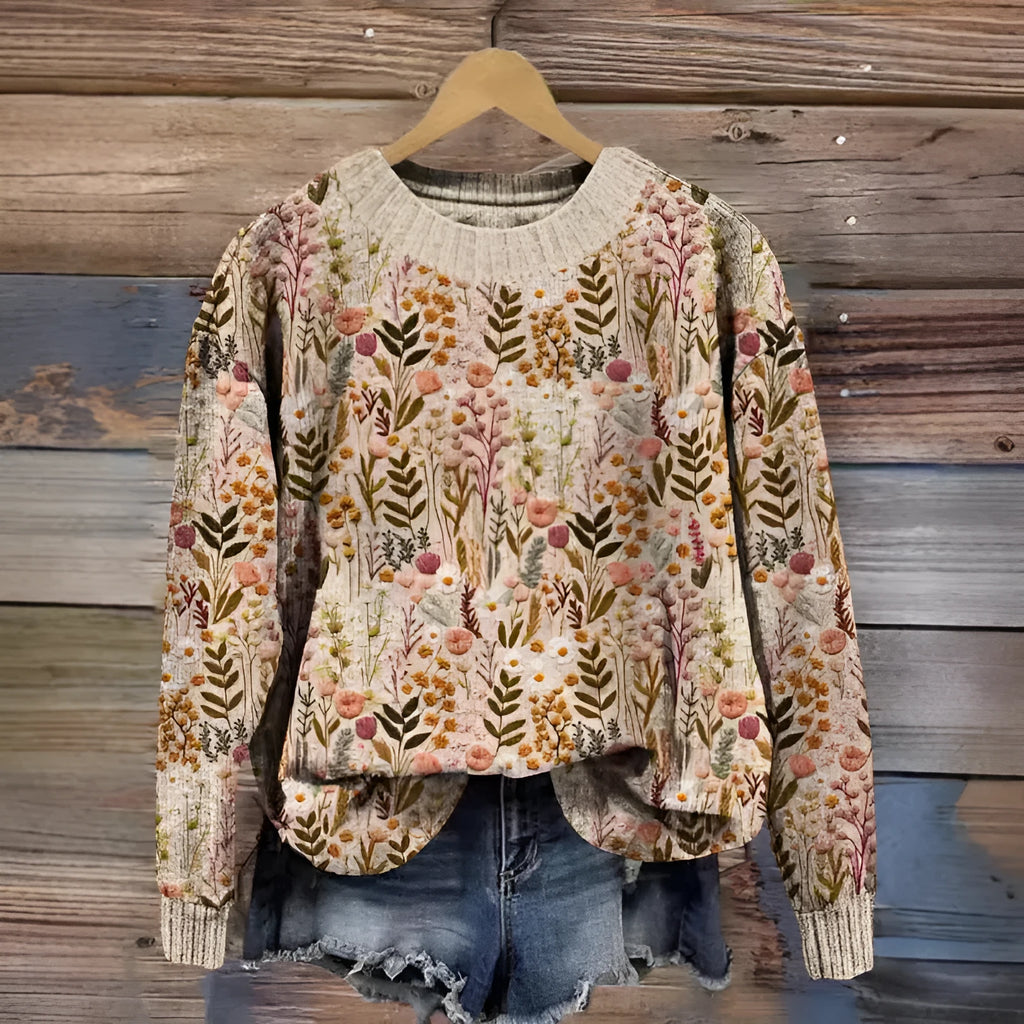 A round neck sweater with a colourful digital floral print, shown on a hanger.