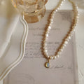 Vintage geometric pearl necklace with adjustable chain on a dark background.