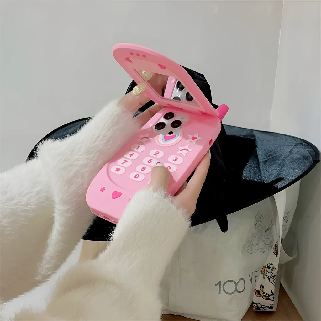 Pink silicone flip phone case for iPhone with a built-in compact mirror on the front.