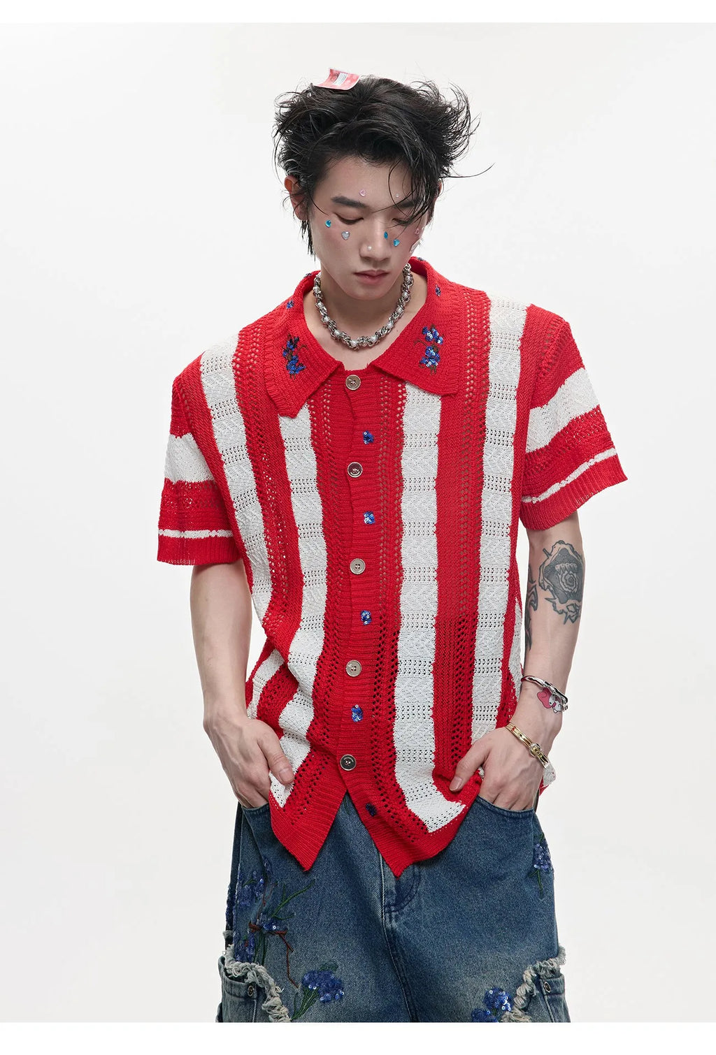 Man wearing a red and black patchwork striped knitted short-sleeved shirt with a loose fit.