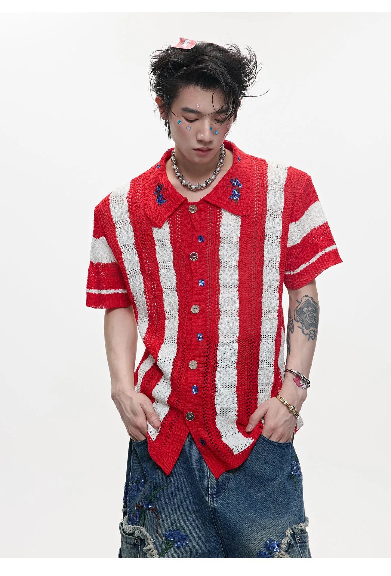 Man wearing a red and black patchwork striped knitted short-sleeved shirt with a loose fit.
