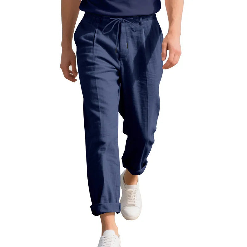 Men's light khaki linen trousers with a drawstring waist and straight leg on a hanger.