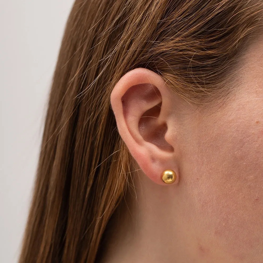 Minimalist round ball stud earrings in gold and silver plating on a white background.