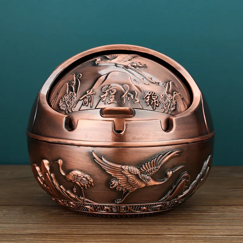 Alloy decorative ashtray in bronze with ornate peacock motif and cigarette extinguishing slot.