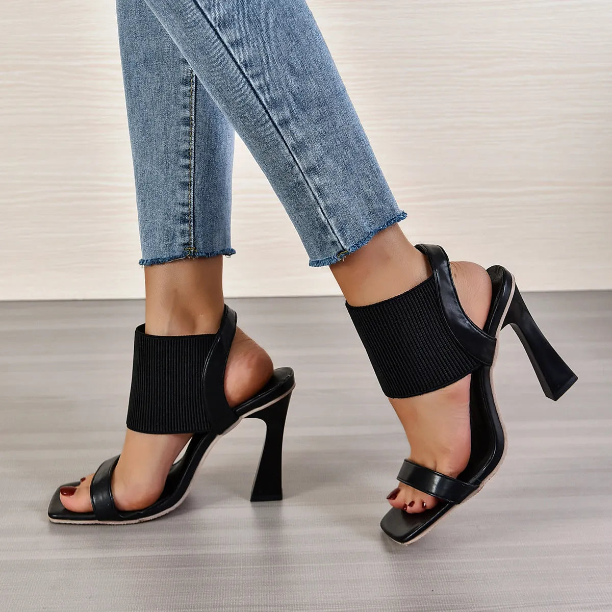 Women's black high heel sandals with a thin elastic strap across the foot.
