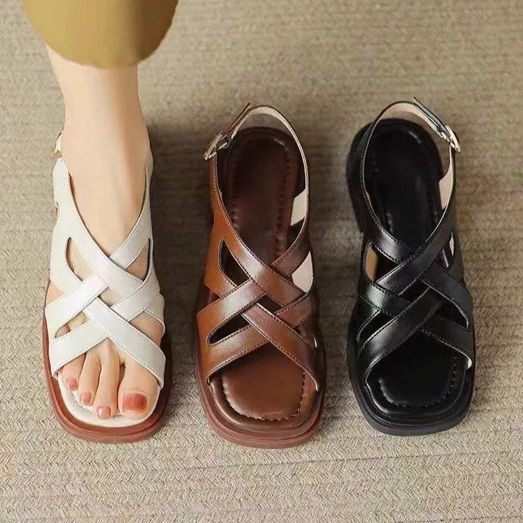 Women's glossy patent leather sandals with a square toe and low heel on a solid colour background.