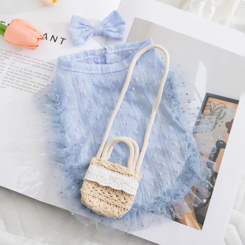 Two-tone blue sleeveless pet outfit with ruffles, matching bow, and small woven crossbody bag on a small dog