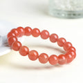 Natural cherry red agate bead bracelet with polished stones on a neutral background, showing single strand and bead detail.