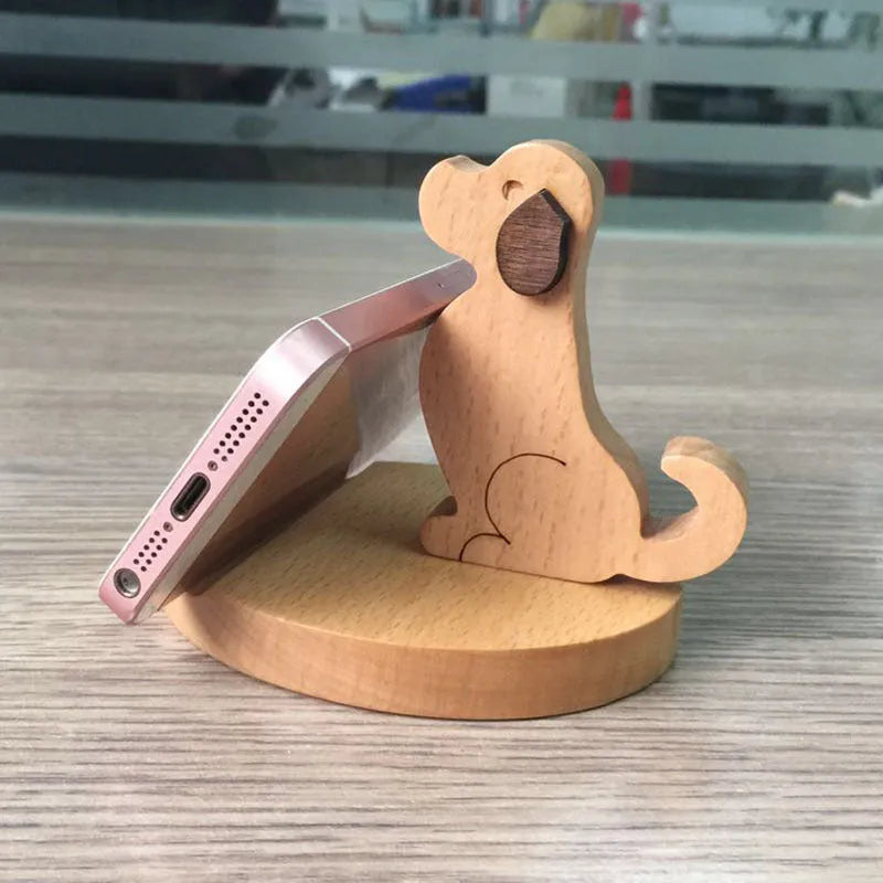 A decorative mobile phone stand made of light beech wood with a detailed resin elephant figure on top, holding a smartphone.