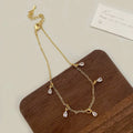 A zircon jewellery set comprising a geometric pendant necklace, stud earrings, and an anklet on a white background.