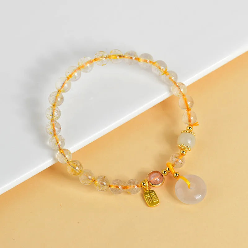 Gold rutilated quartz bracelet with safety buckle and geometric blessing card pendant.