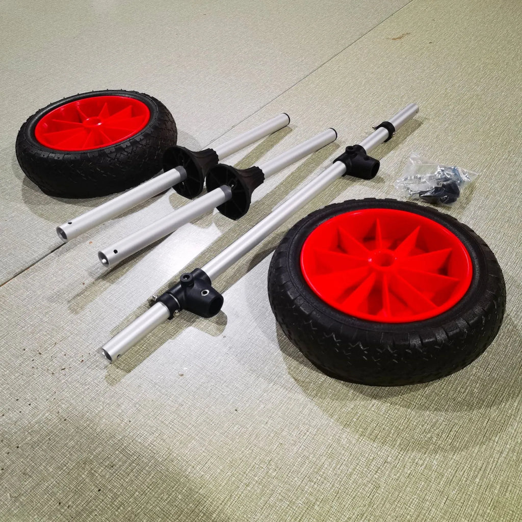 Foldable aluminium kayak trolley with large black pneumatic tyres on a beach, shown carrying a yellow kayak.