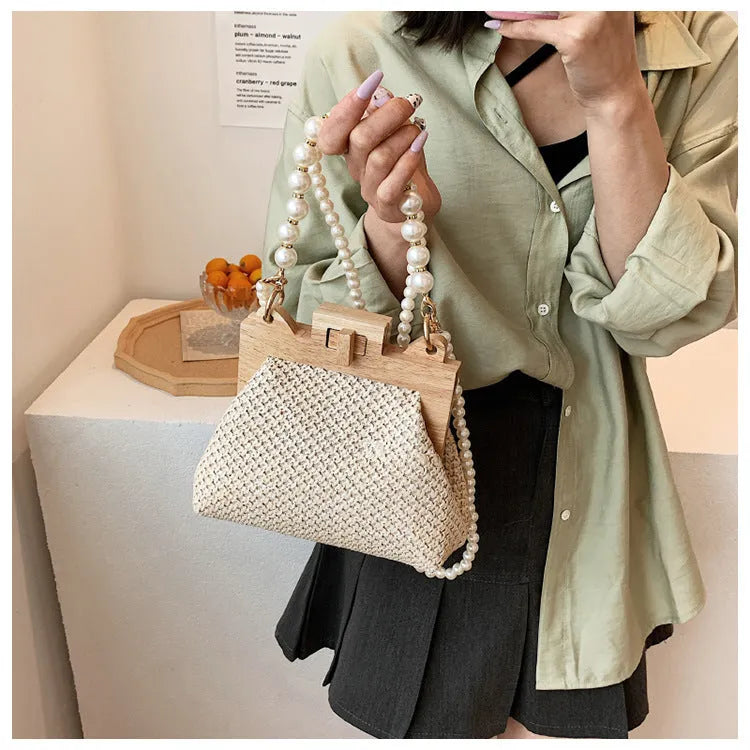 Women's woven straw shoulder bag with pearl chain strap showing internal organisation compartments