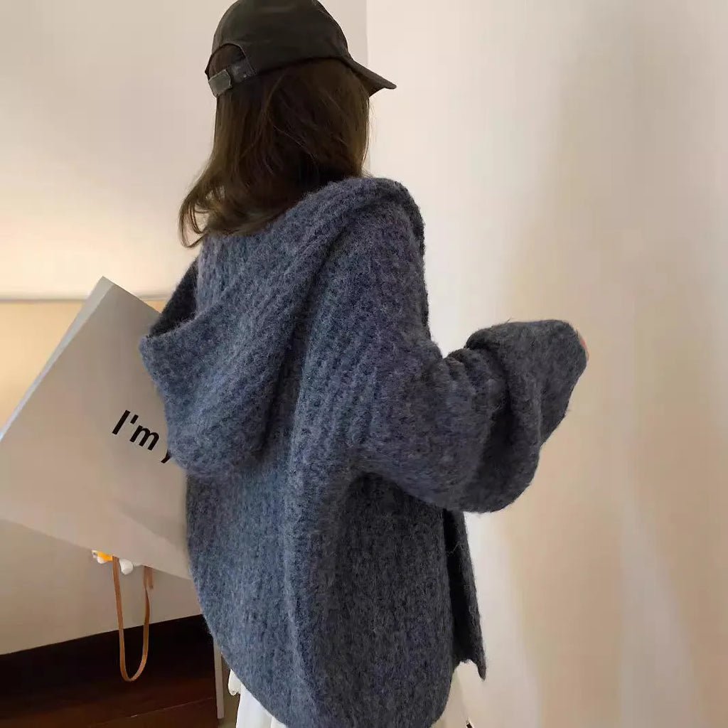 A woman wearing a thick, dark grey hooded cardigan with a loose, longline fit.