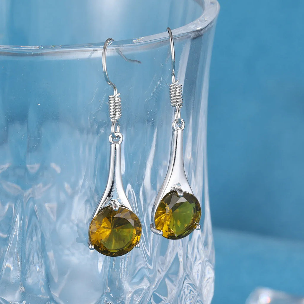 Olive green topaz coloured drop-shaped fashion earrings with a retro style on a white background.
