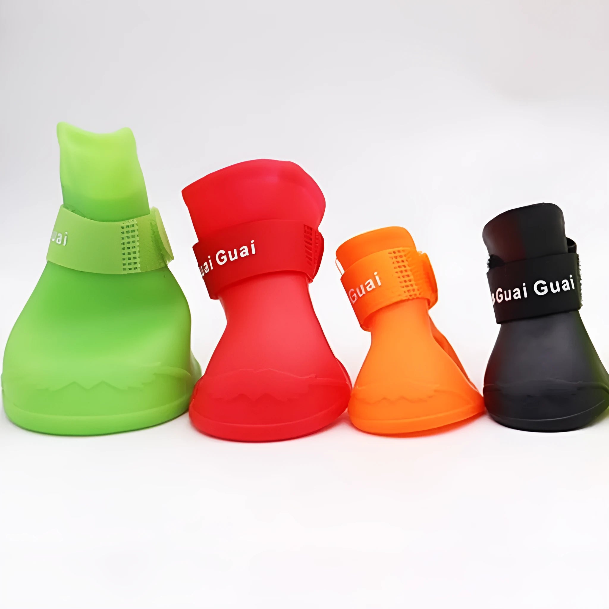 A set of four colourful rubber rain shoes for dogs, showing soft soles and bright pink, blue, orange, and red colours.
