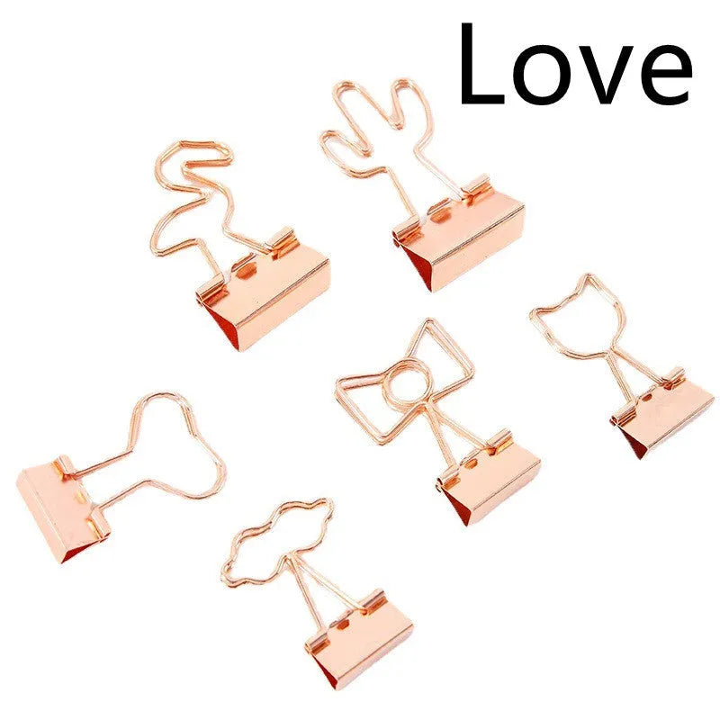 Small gold-plated metal office clip with a long tail, shown in decorative flamingo, love, cat, cactus, and bow shapes.