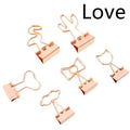 Small gold-plated metal office clip with a long tail, shown in decorative flamingo, love, cat, cactus, and bow shapes.