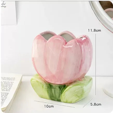 Ceramic pen holder box with floral decoration on a desk, holding pens.