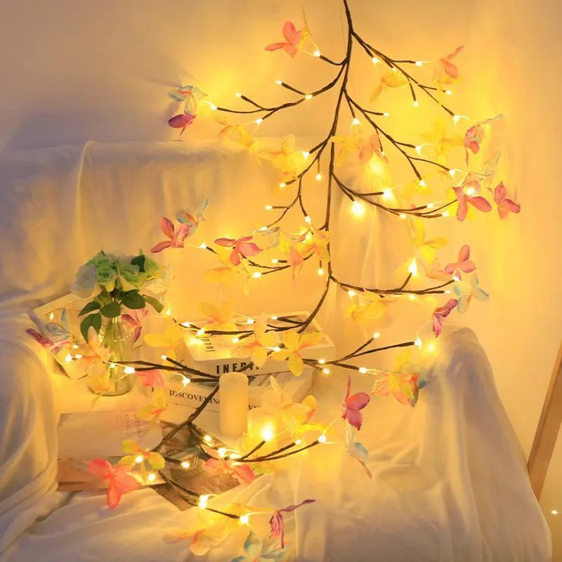 Tall flexible LED rattan tree lamp with colour-changing butterfly decorations lit up.