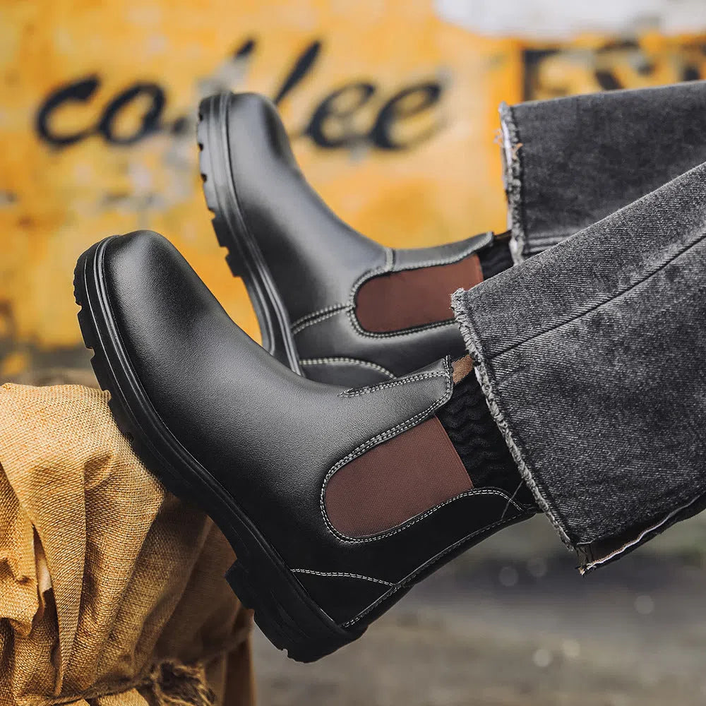 Chelsea boots in black with low wedge heel, round toe, and mid-calf shaft on a neutral background